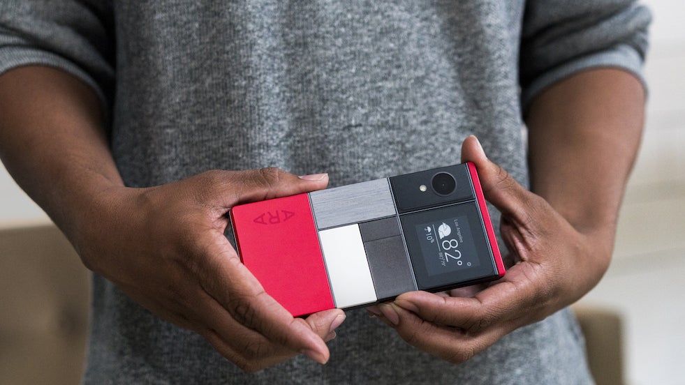 A person holding a Project Ara prototype, a red frame with camera, display and blank modules slotted into the back